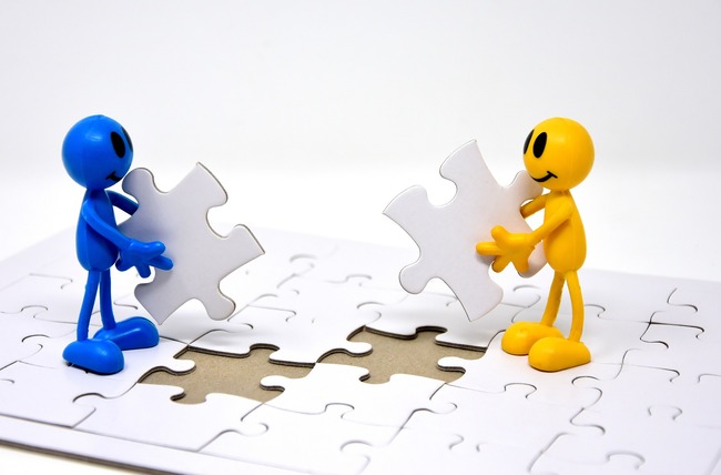 two figurines holding pieces of a jigsaw puzzle