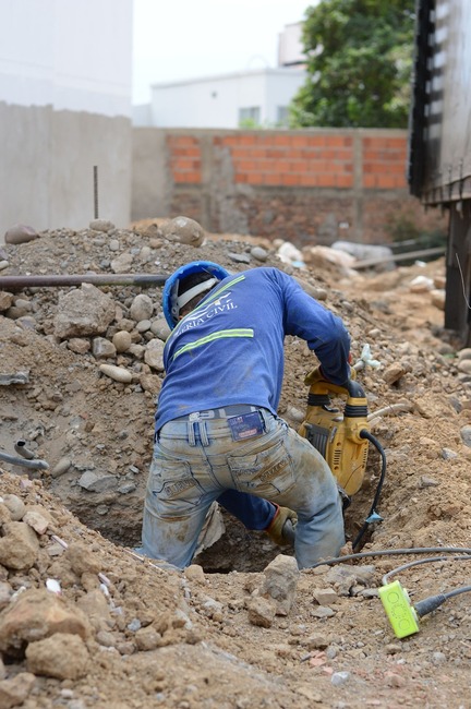 construction worker in hole working with power tool