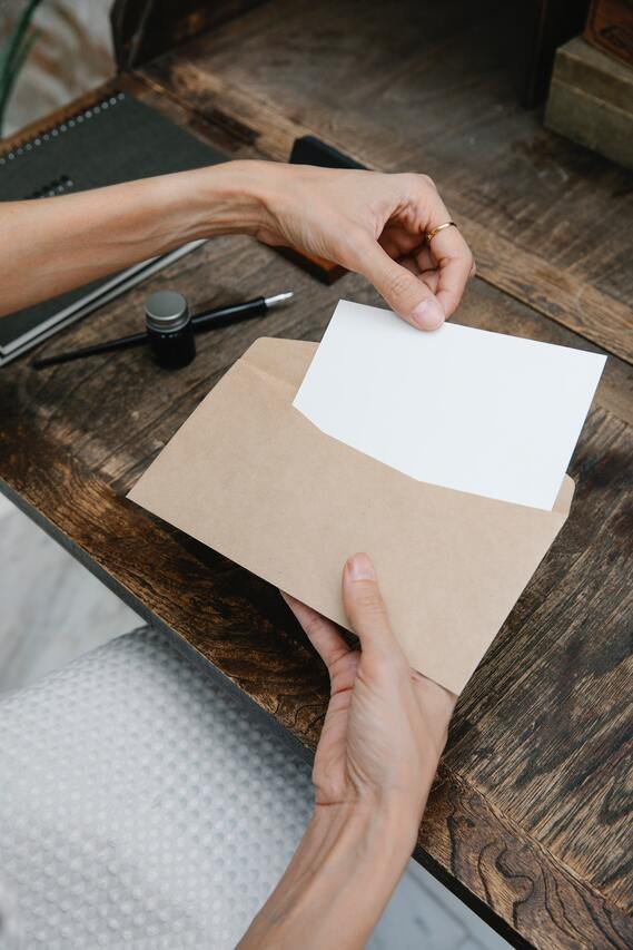 woman's hand placing letter inside an envelope
