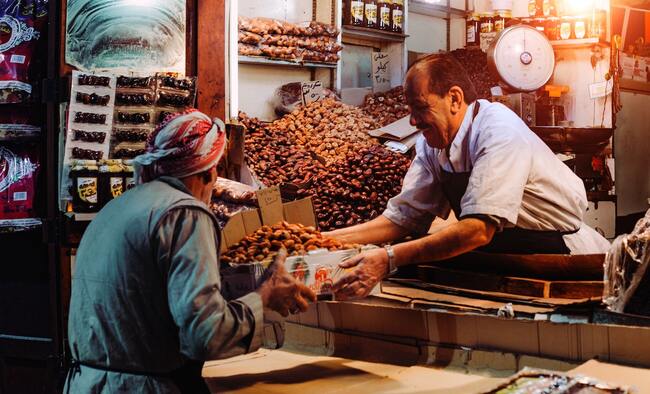 shopkeeper handing a box of nuts to customer