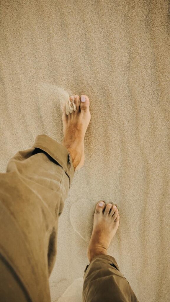 Man with bare feet walking on sand