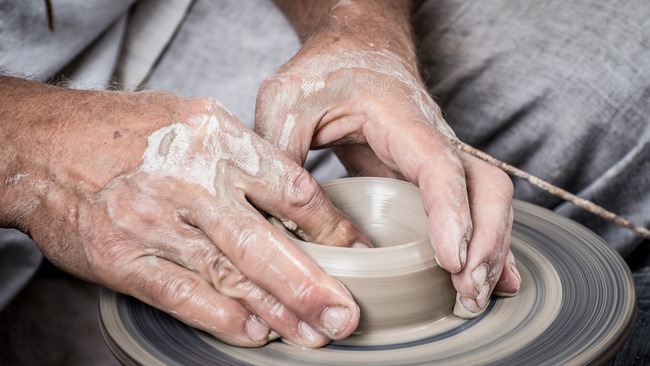 man moulding pottery on a wheel