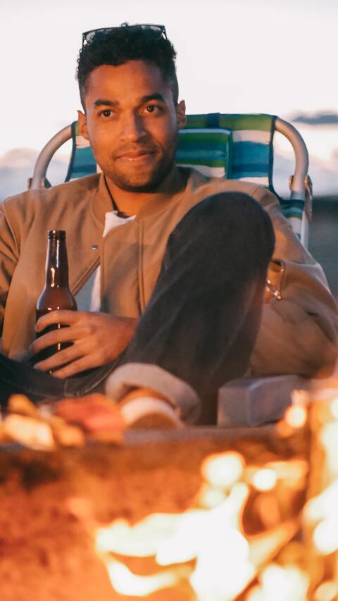 man with beer in front of fire