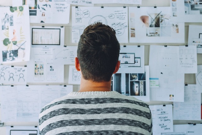 man looking at ideas images on wall