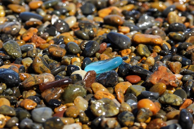 blue glass pebble amongst brown pebbles