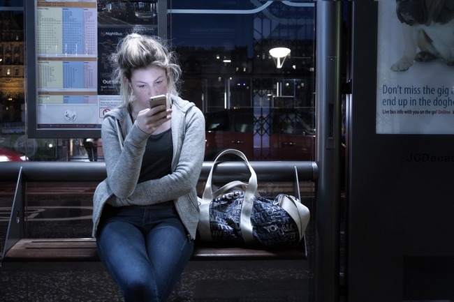 woman looking phone waiting station